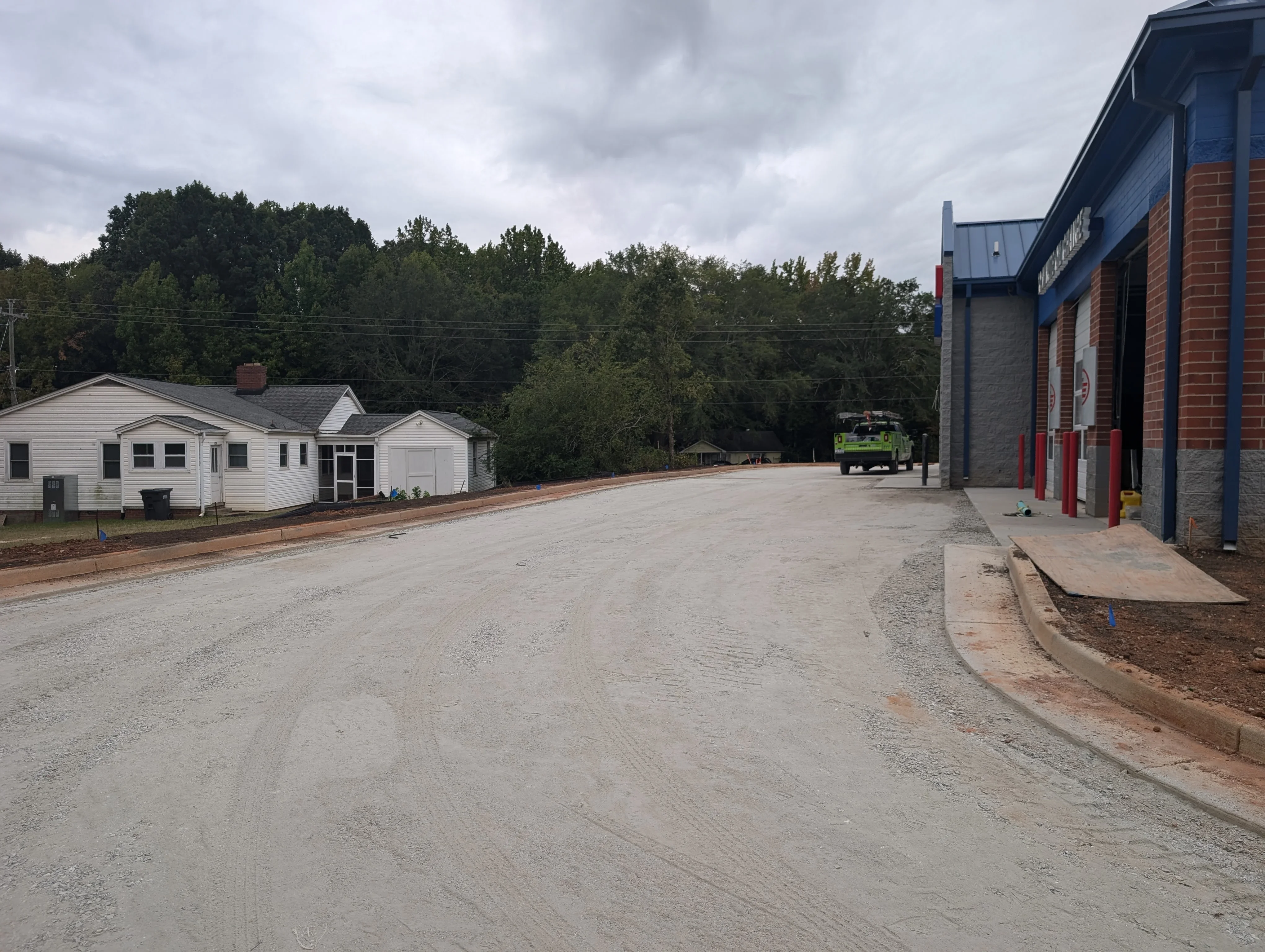 Graded gravel driveway with compacted base, commercial site with brick building and residential structures