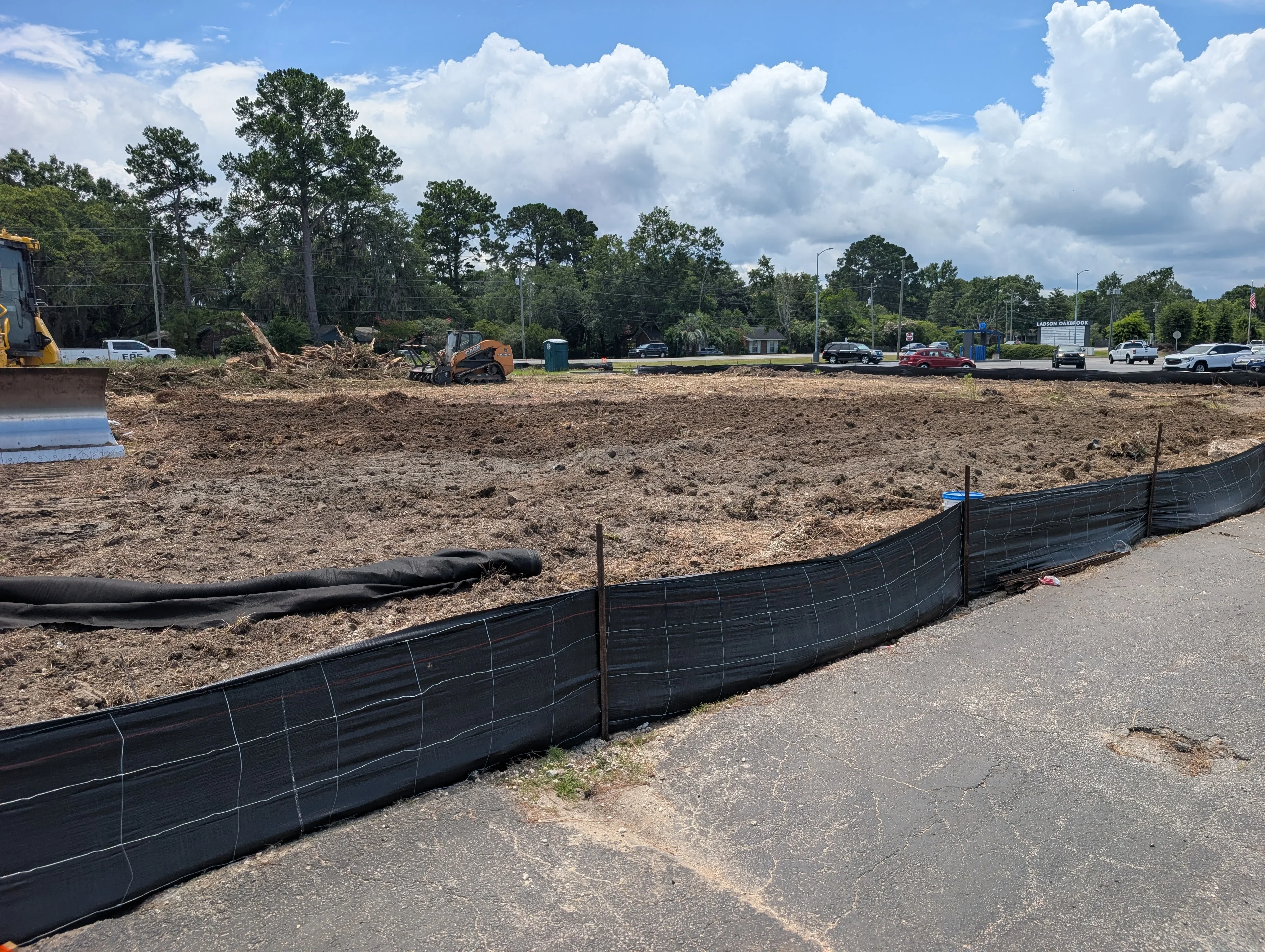 Excavated site with black erosion control fencing, dozers, and graded earth material