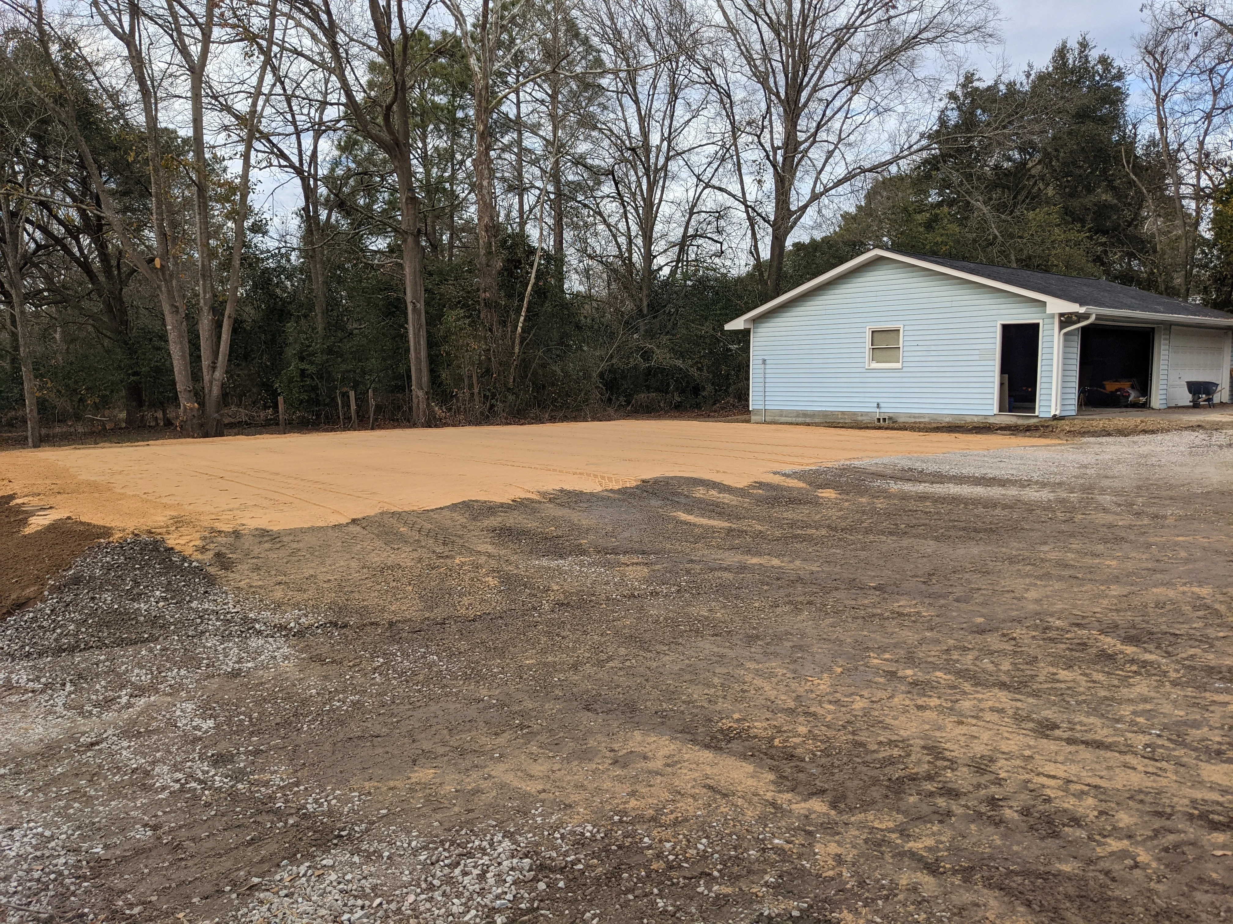 Graded driveway and building pad with compacted fill and gravel base in front of residential structure