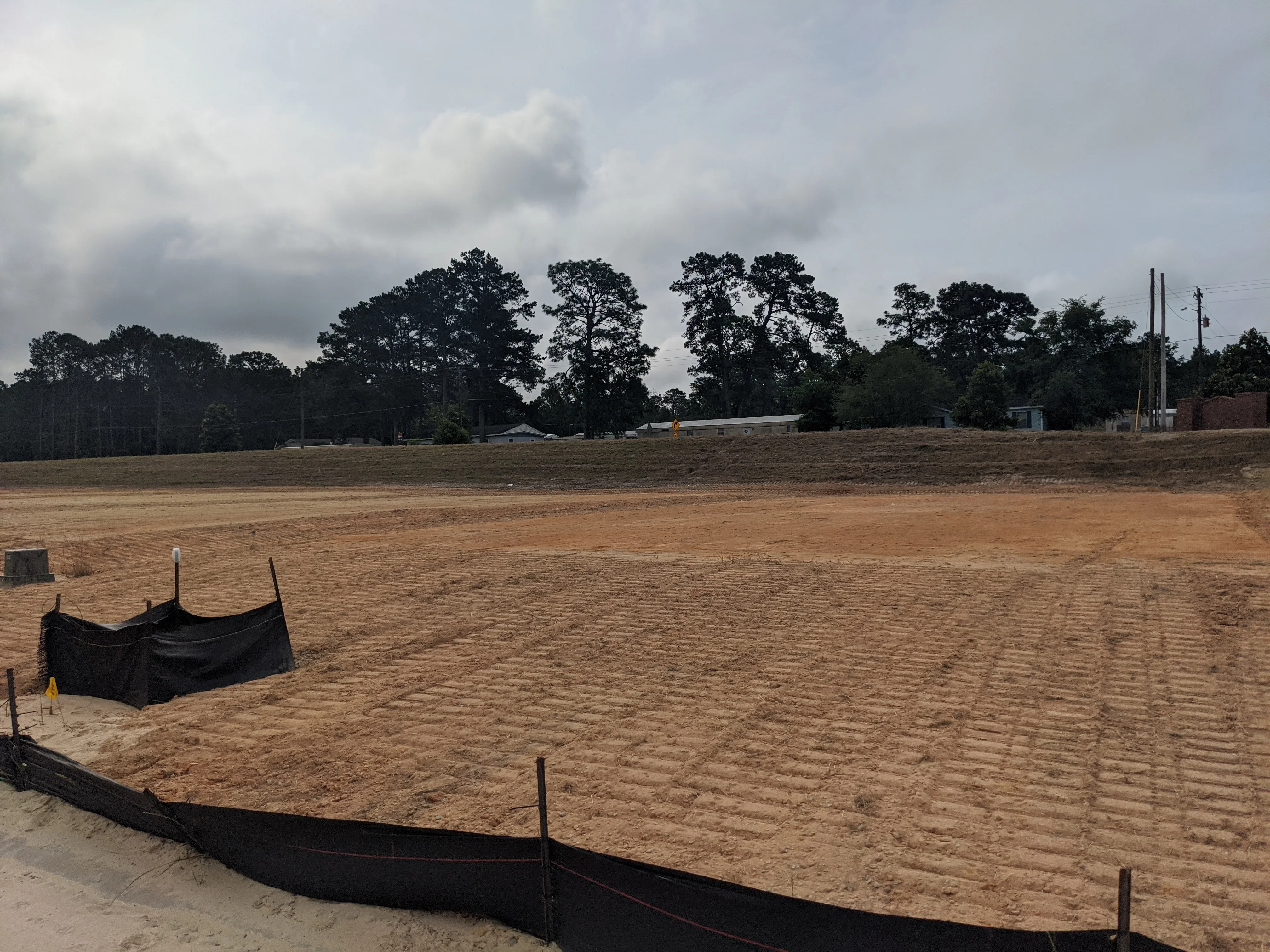 Cleared land with silt fencing, graded soil, and erosion control measures in place