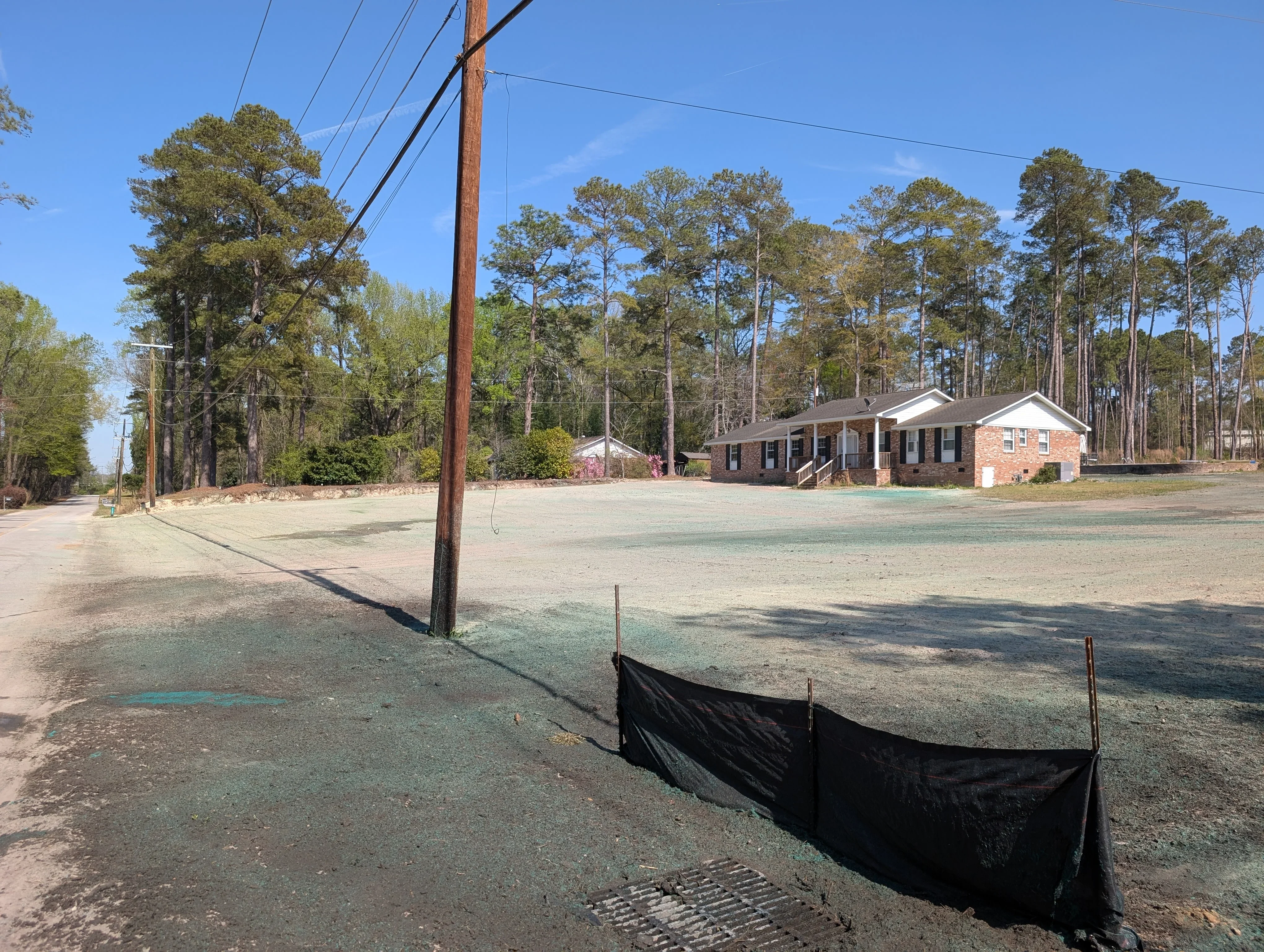 Excavated driveway site with silt fence erosion control and graded base material