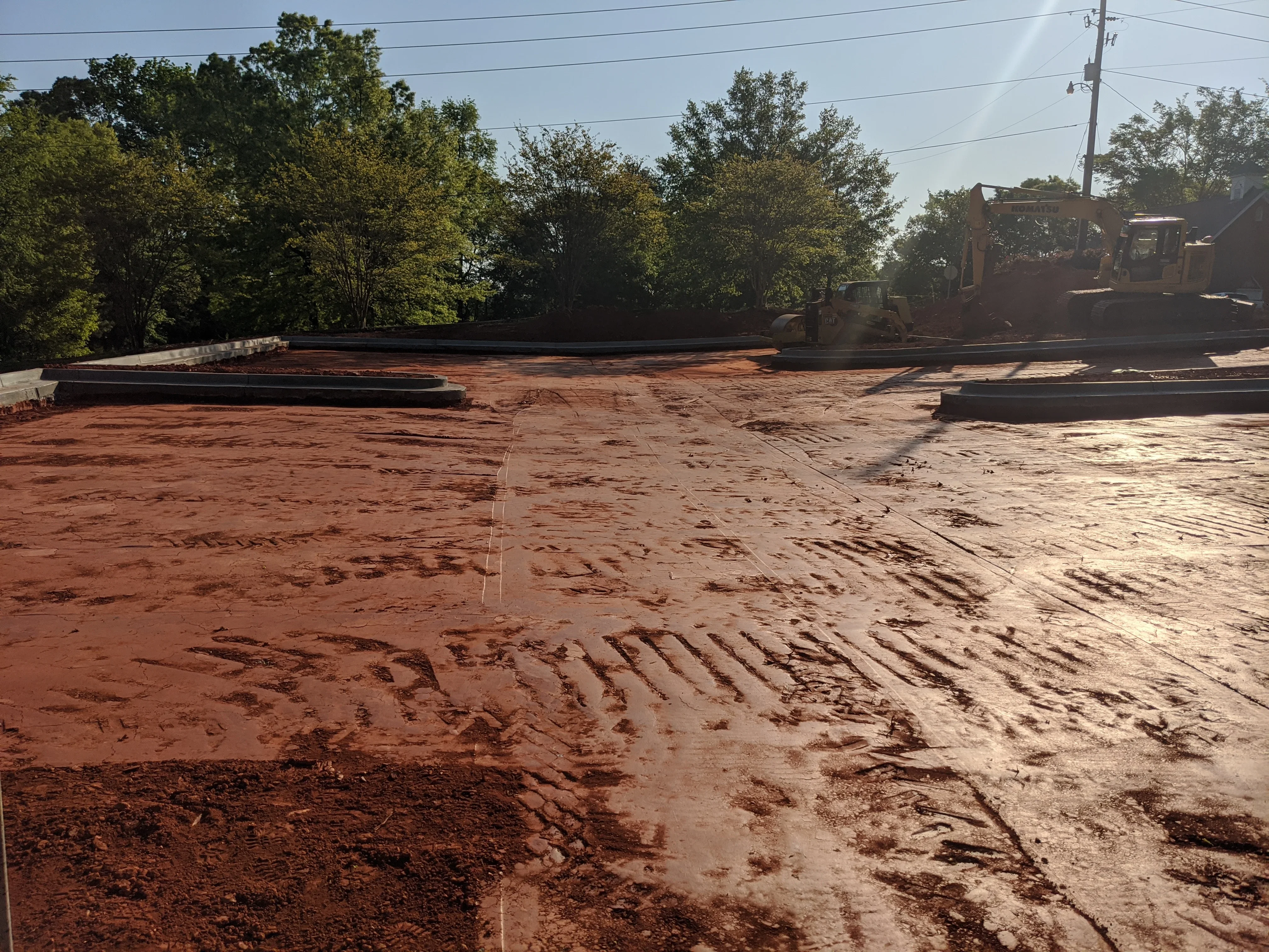 Excavated commercial site with graded earth, steel retaining walls, and heavy equipment