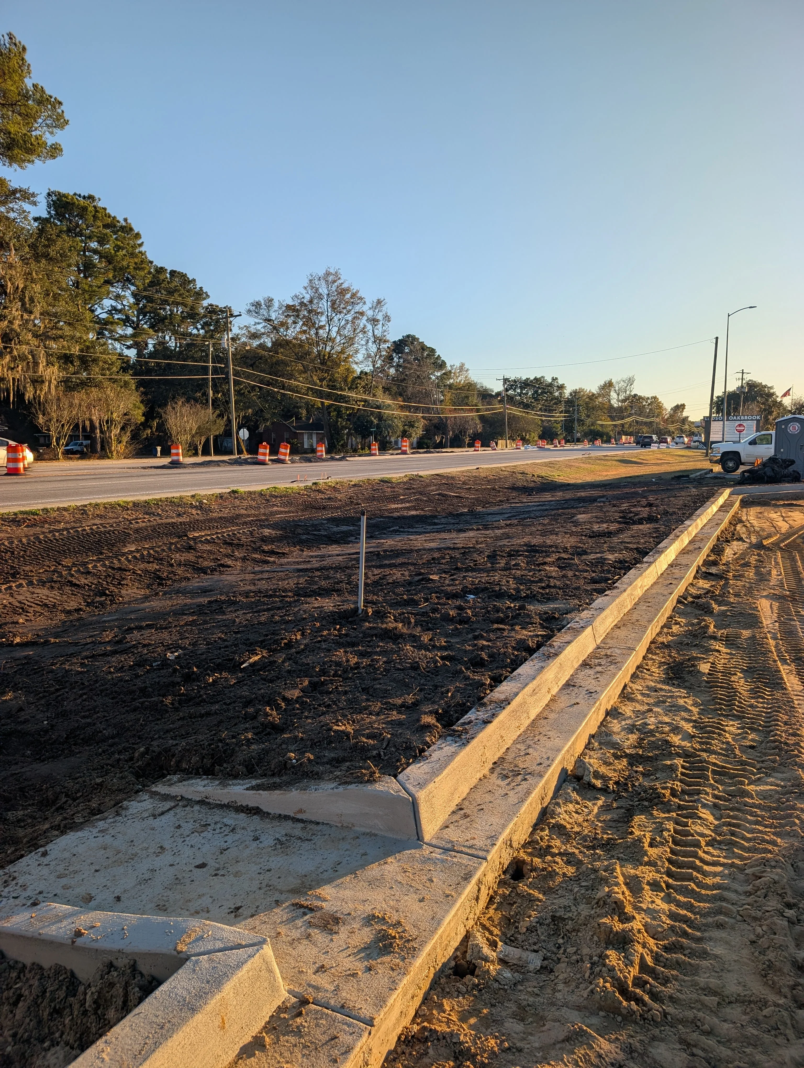 Excavated commercial lot with concrete curbing, graded soil, and drainage channels