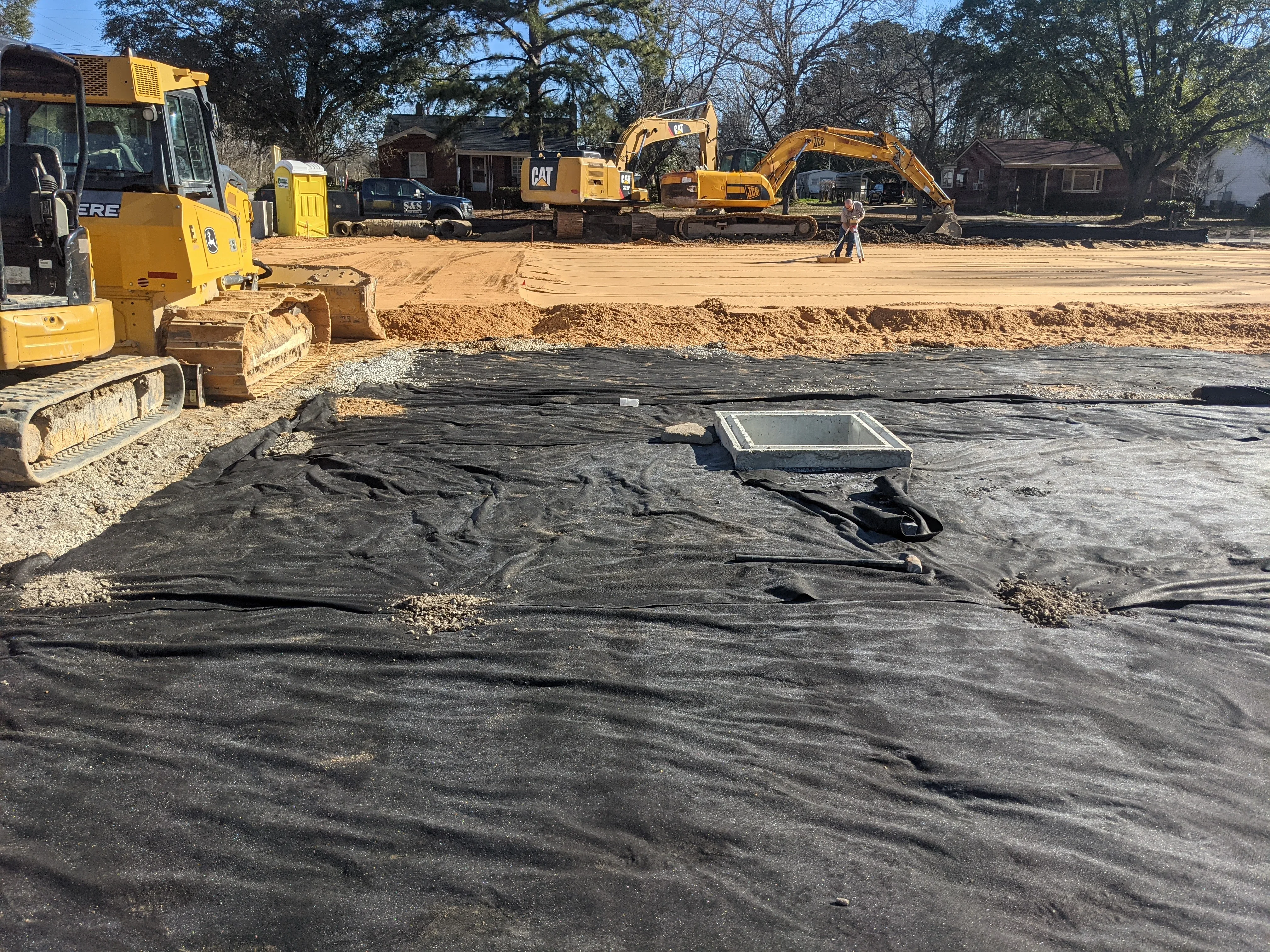 Excavated residential lot with geotextile fabric, dozers, and excavators on-site