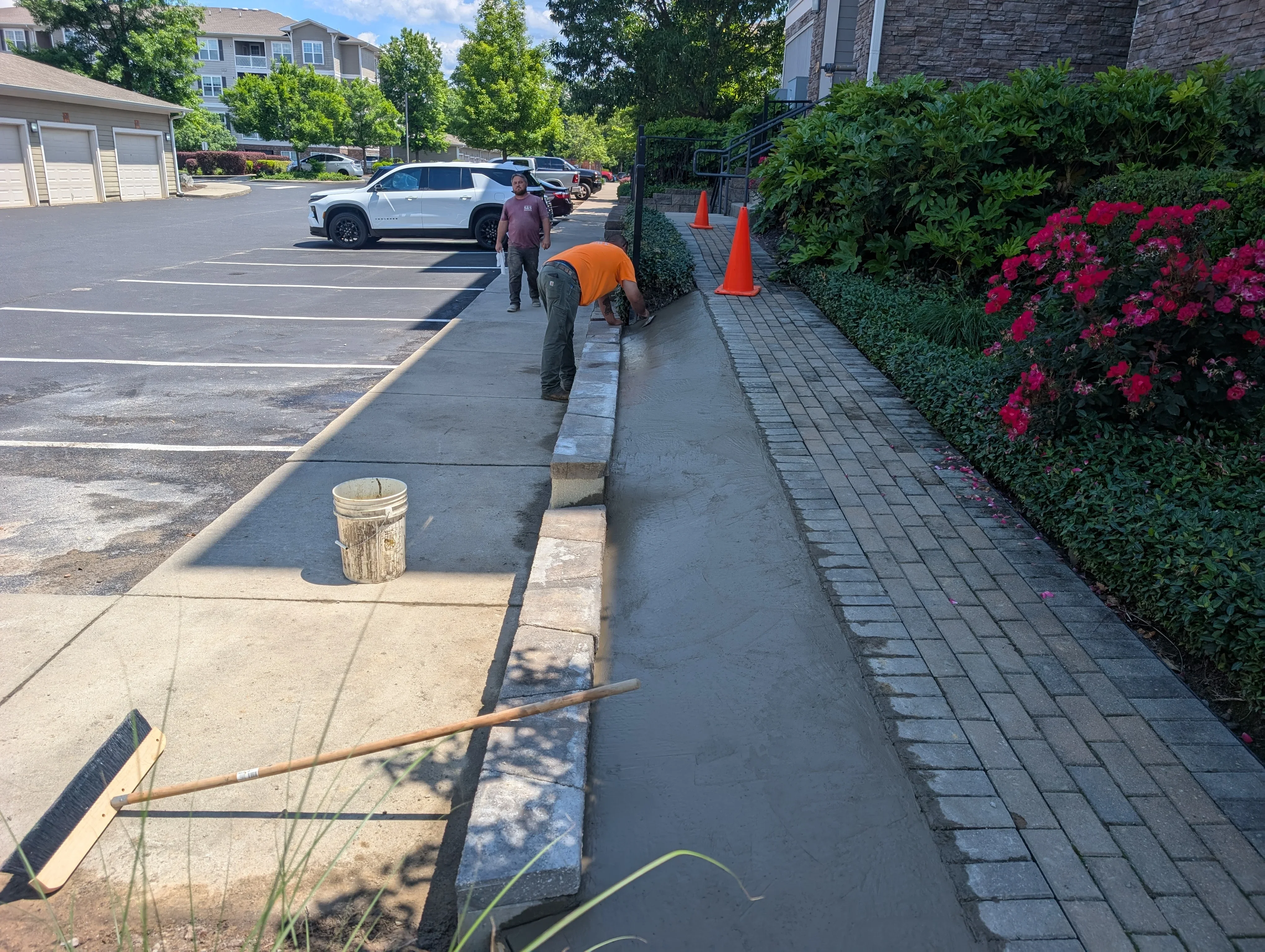 Concrete drainage channel installation with concrete curb and paver edging along parking lot