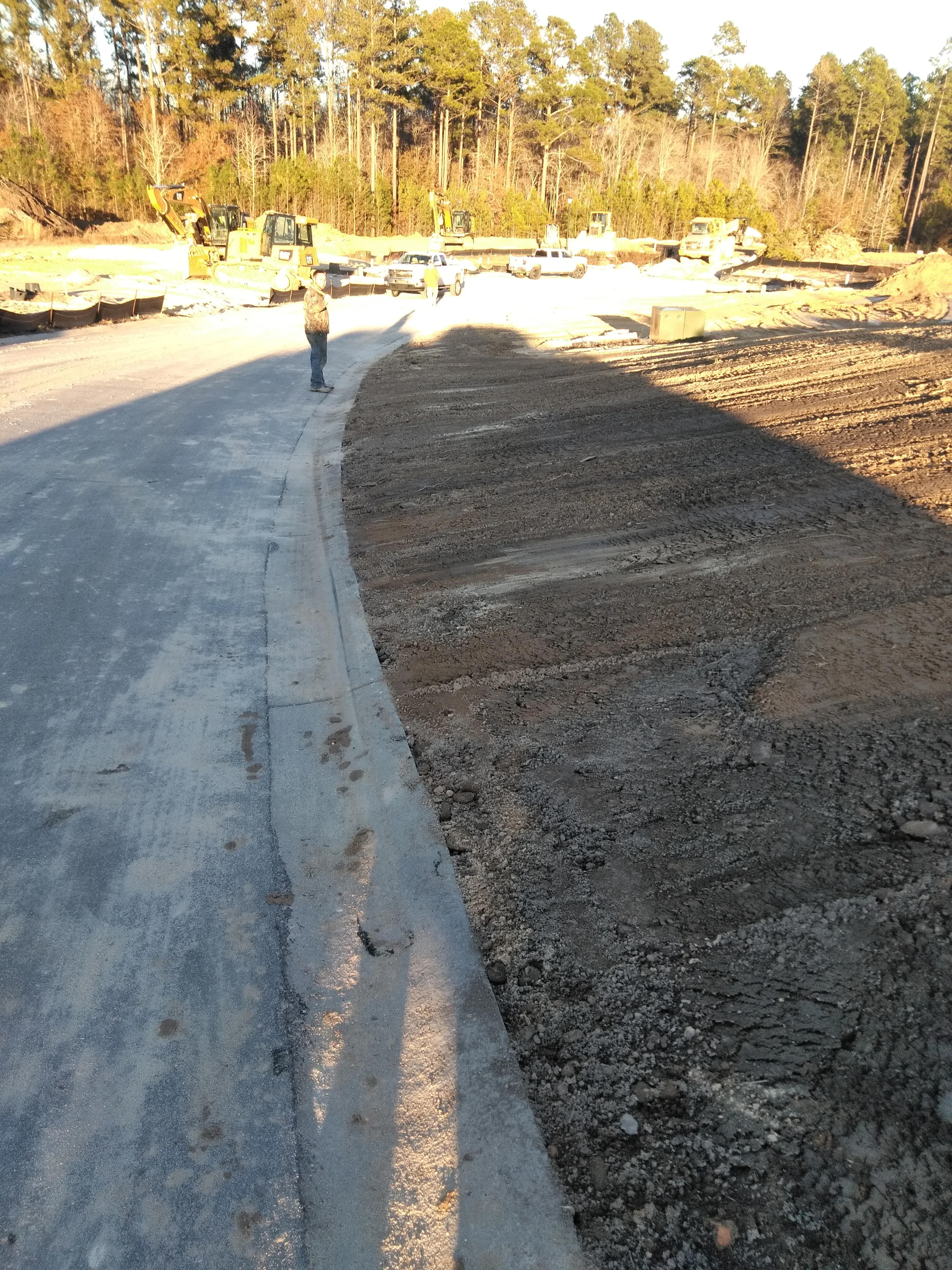 Concrete foundation pad with graded soil base and heavy equipment on cleared site