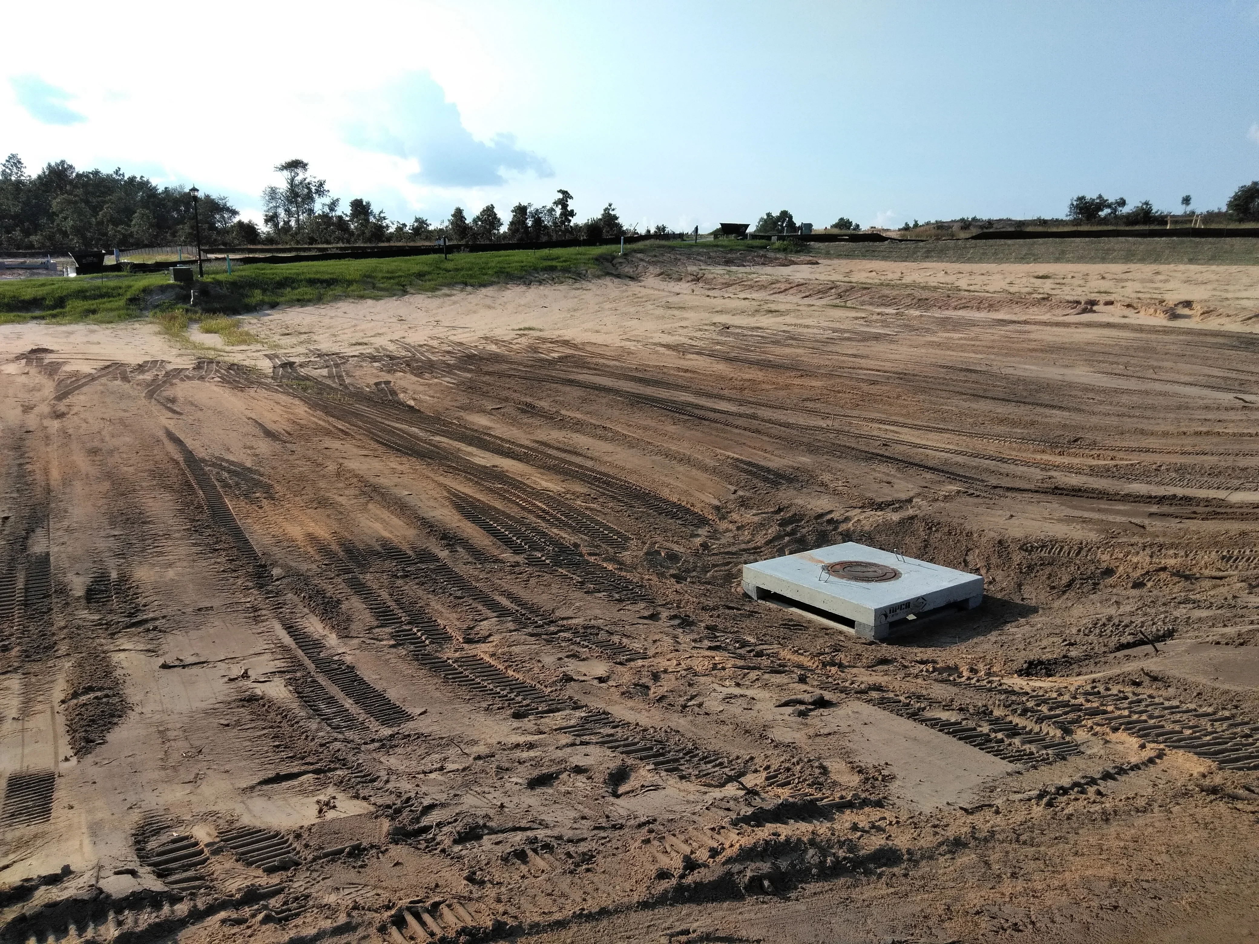 Excavated site with graded soil, equipment tracks, and prepared foundation area