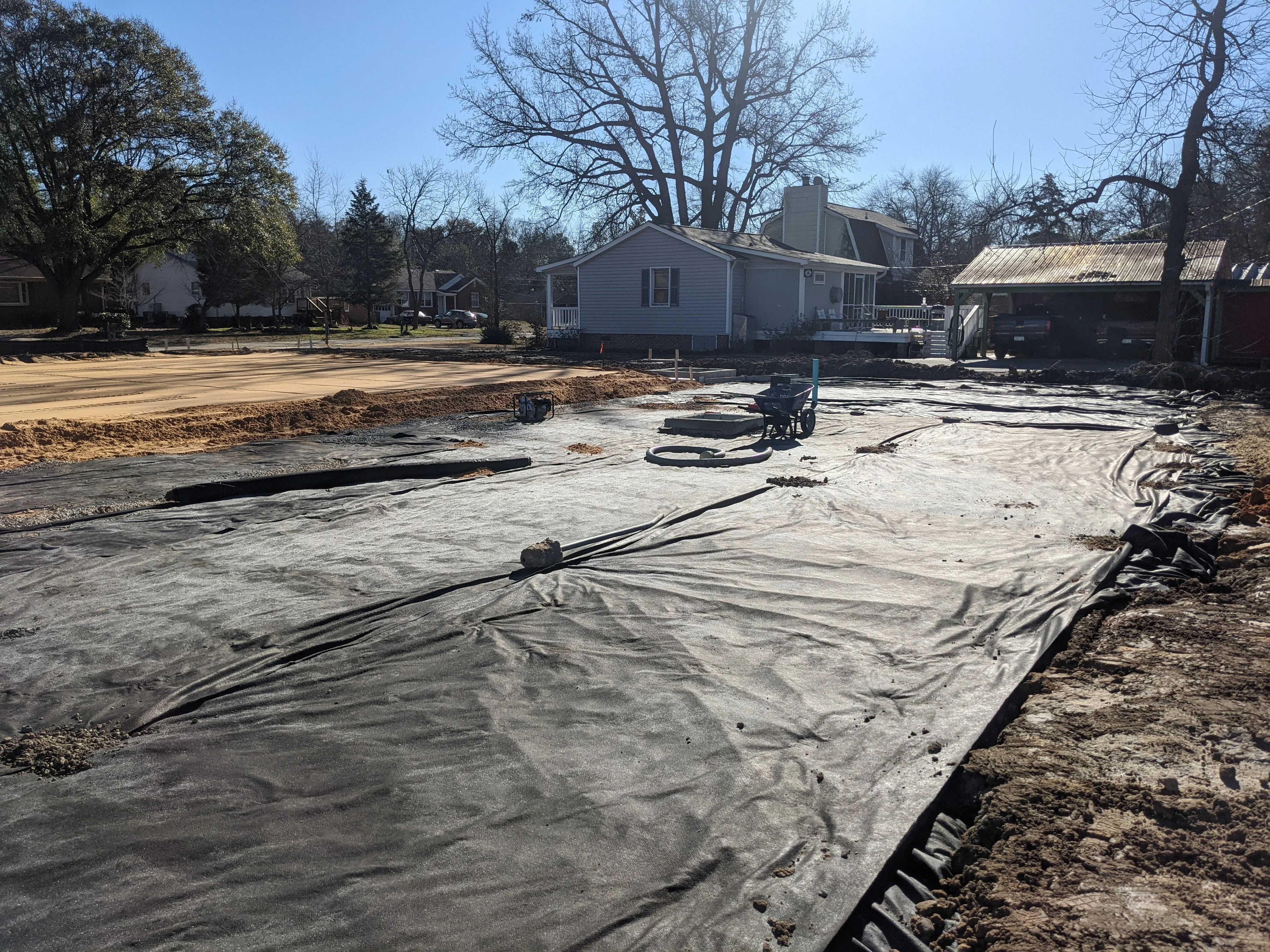 Excavated residential lot with erosion control fabric, graded soil, and preparation for construction