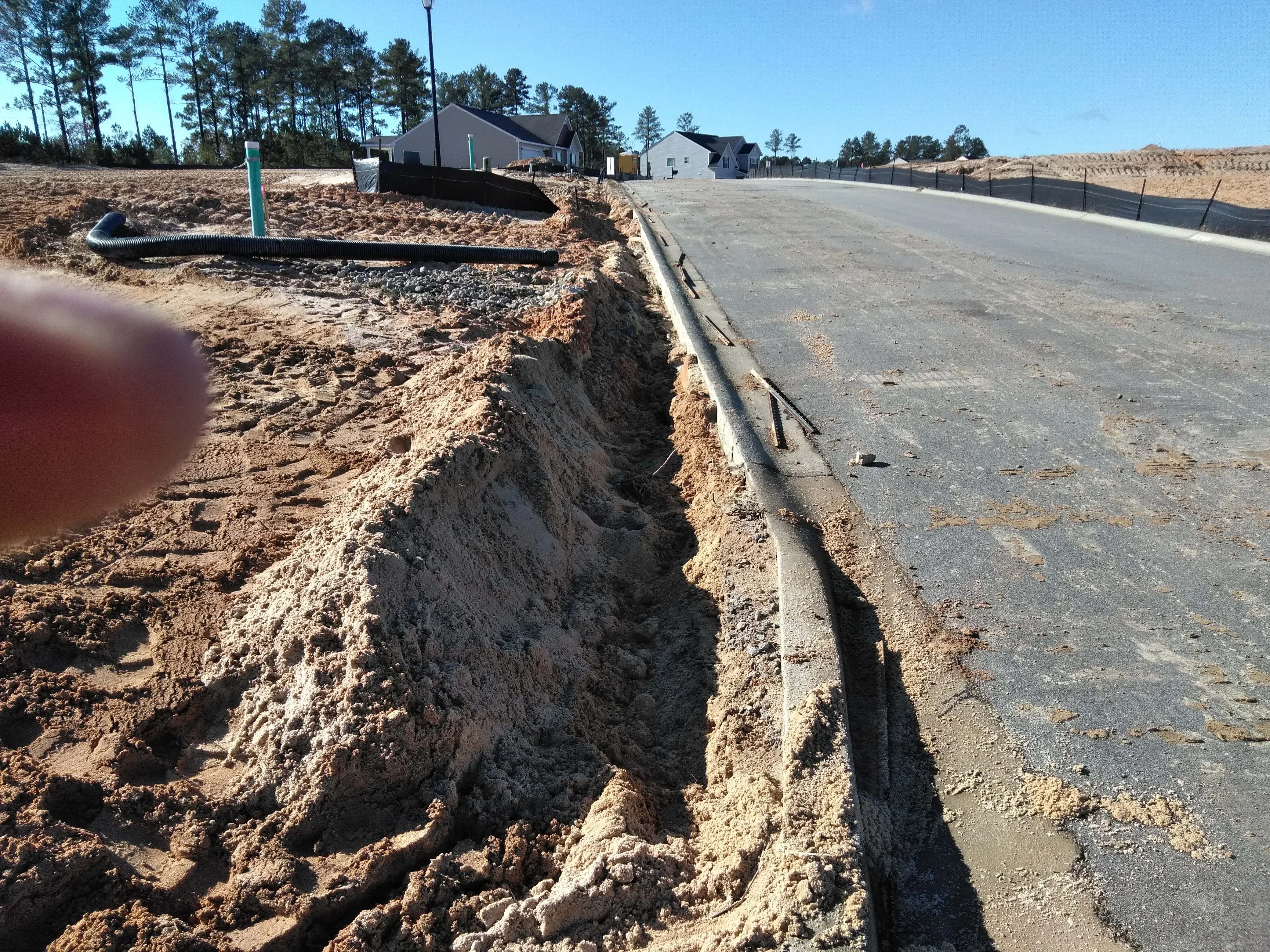 Excavated driveway trench with concrete curb edge and graded site preparation