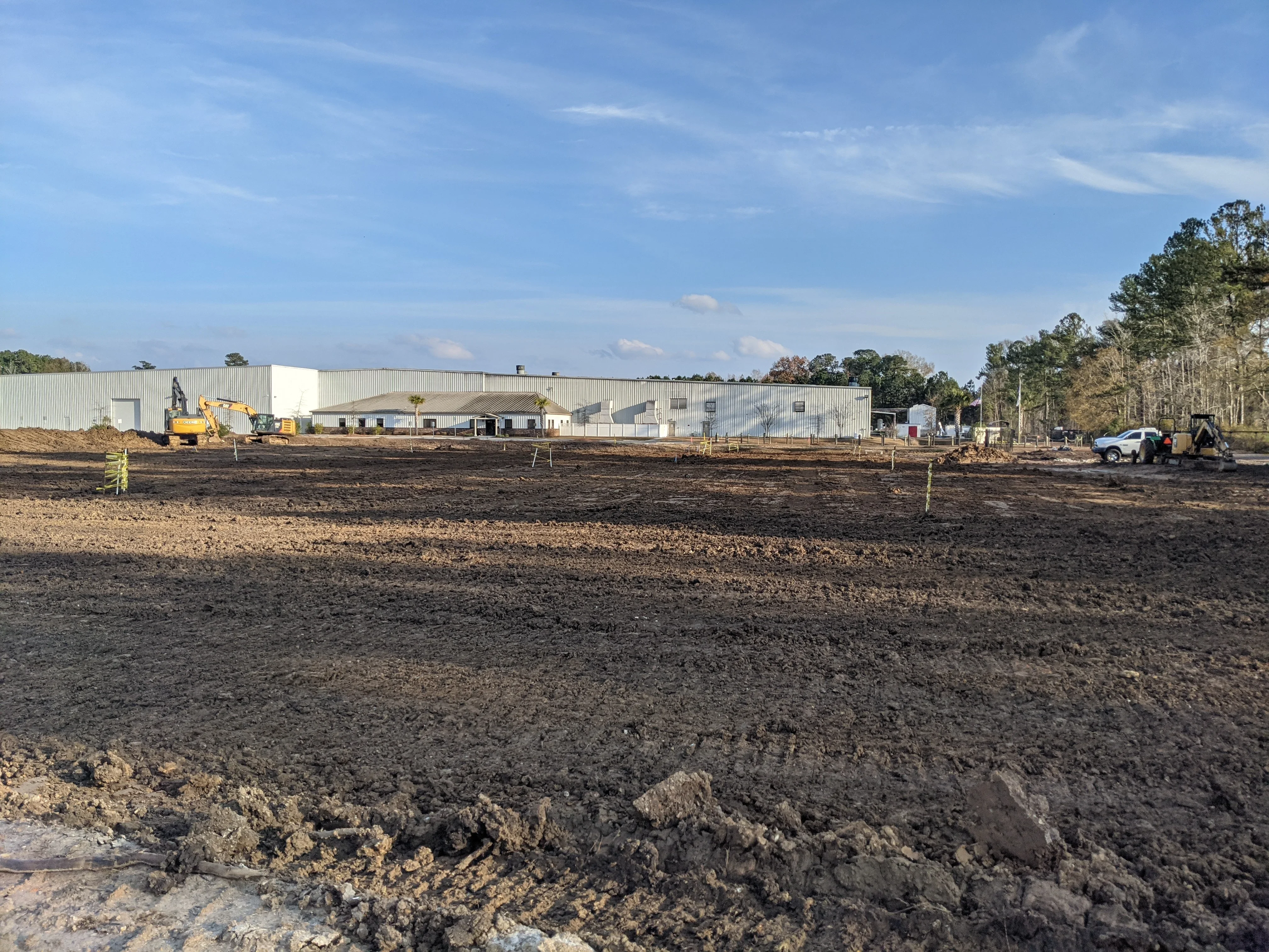 Excavated and graded commercial lot with heavy equipment and metal building structure