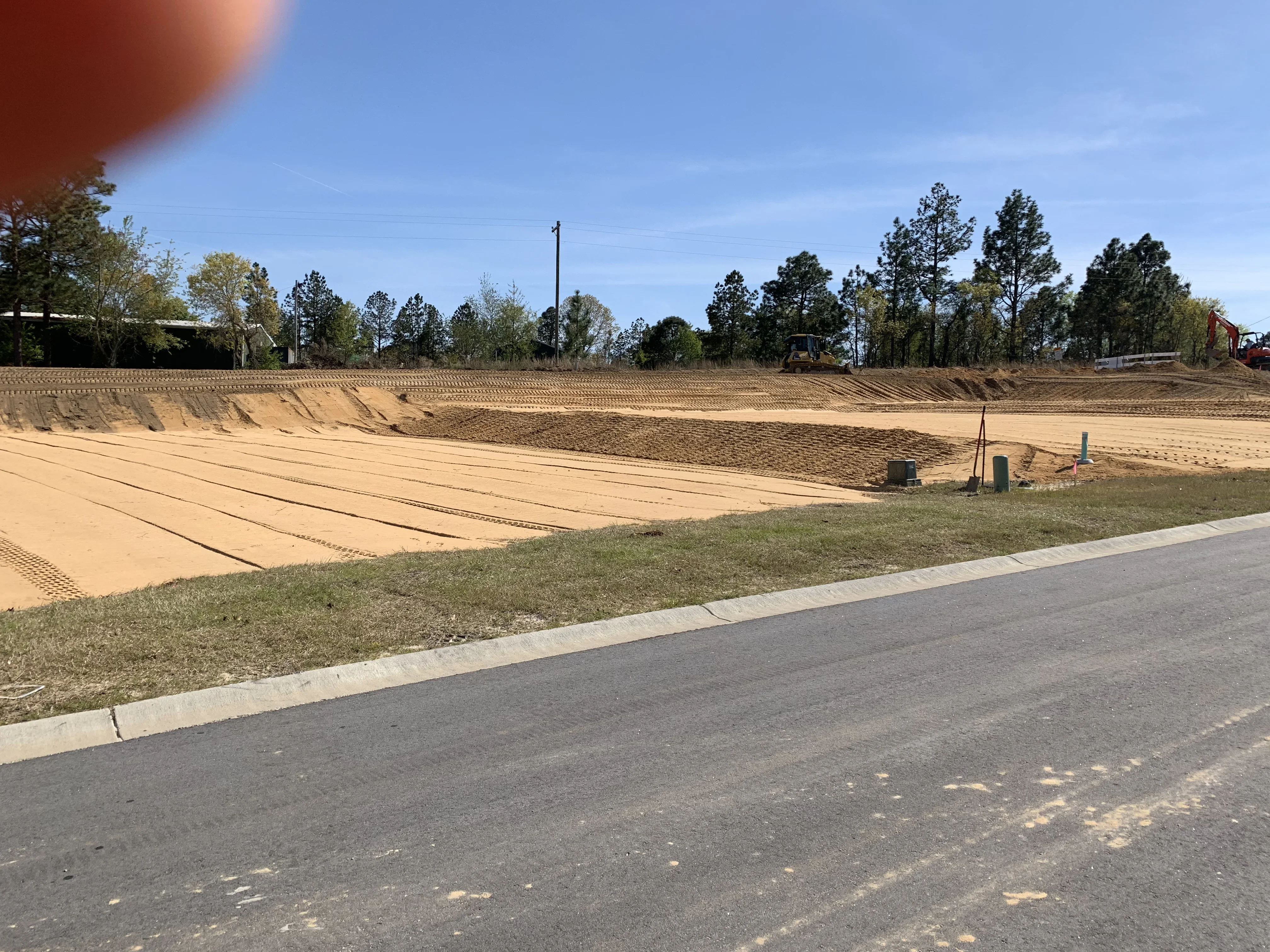 Graded commercial site with compacted soil, concrete curbing, and contoured earthwork