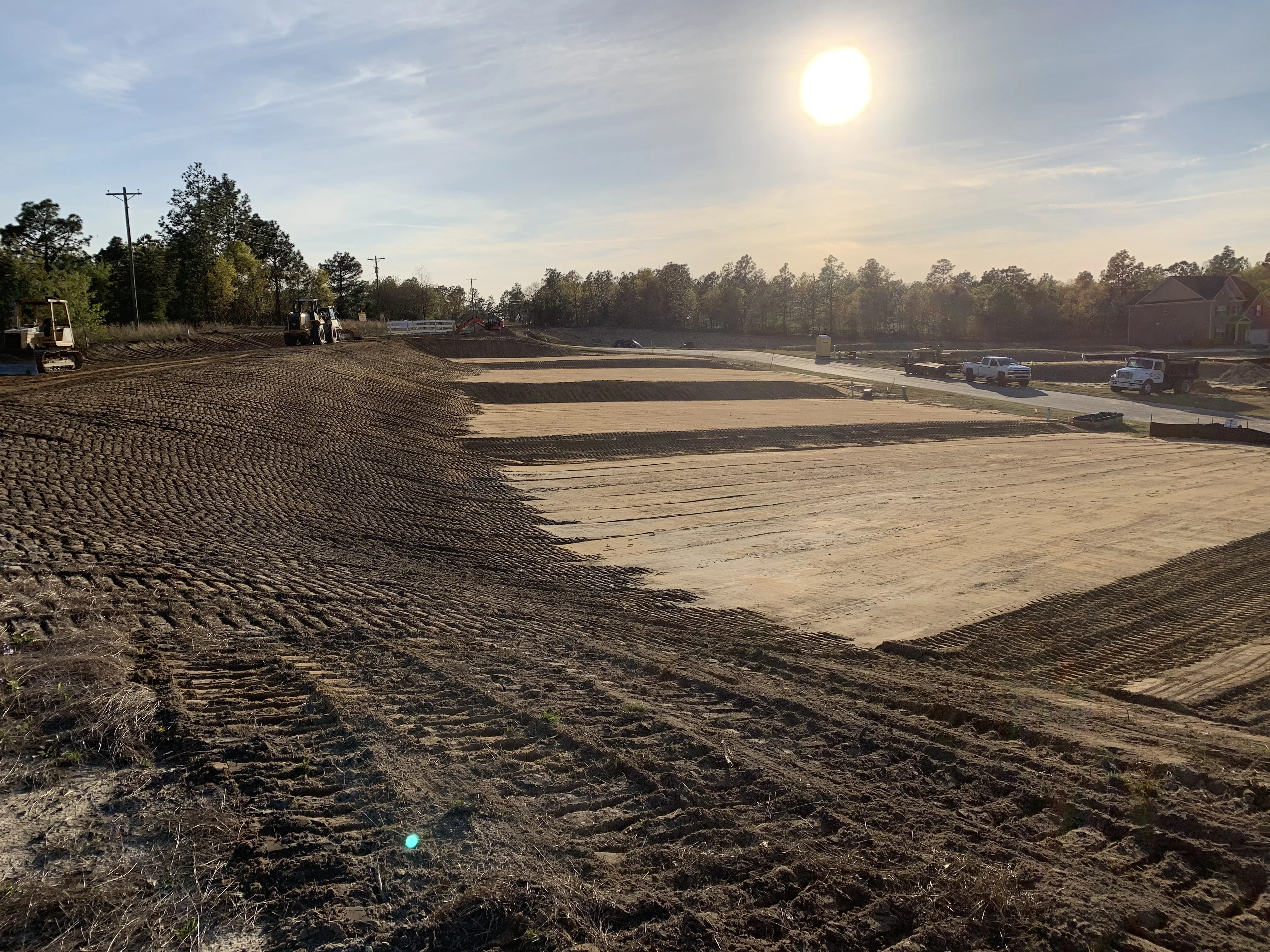 Excavated commercial site with graded soil, erosion control fabric, and heavy equipment during site preparation