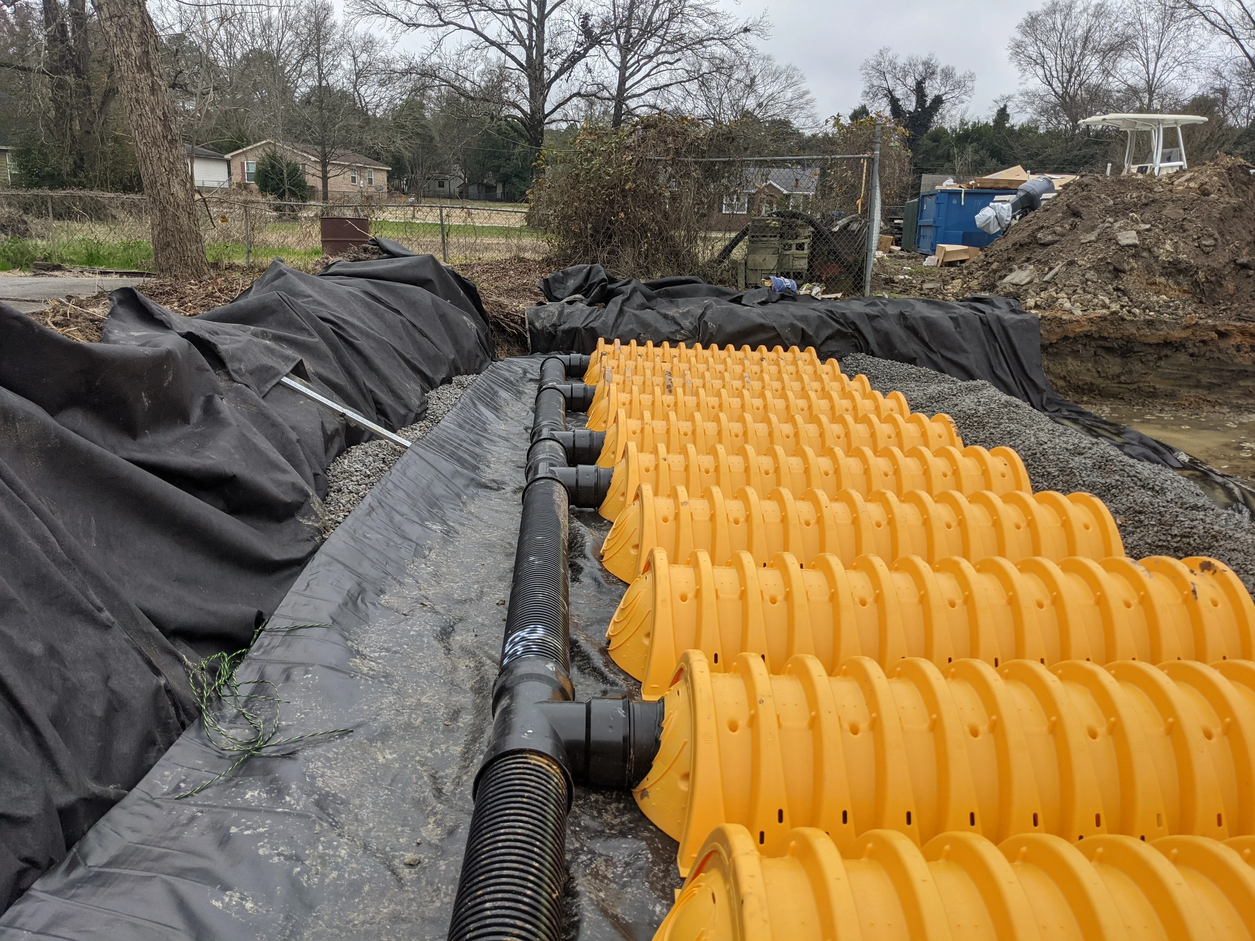 Corrugated drainage pipe with yellow catch basins and landscape fabric in gravel bed
