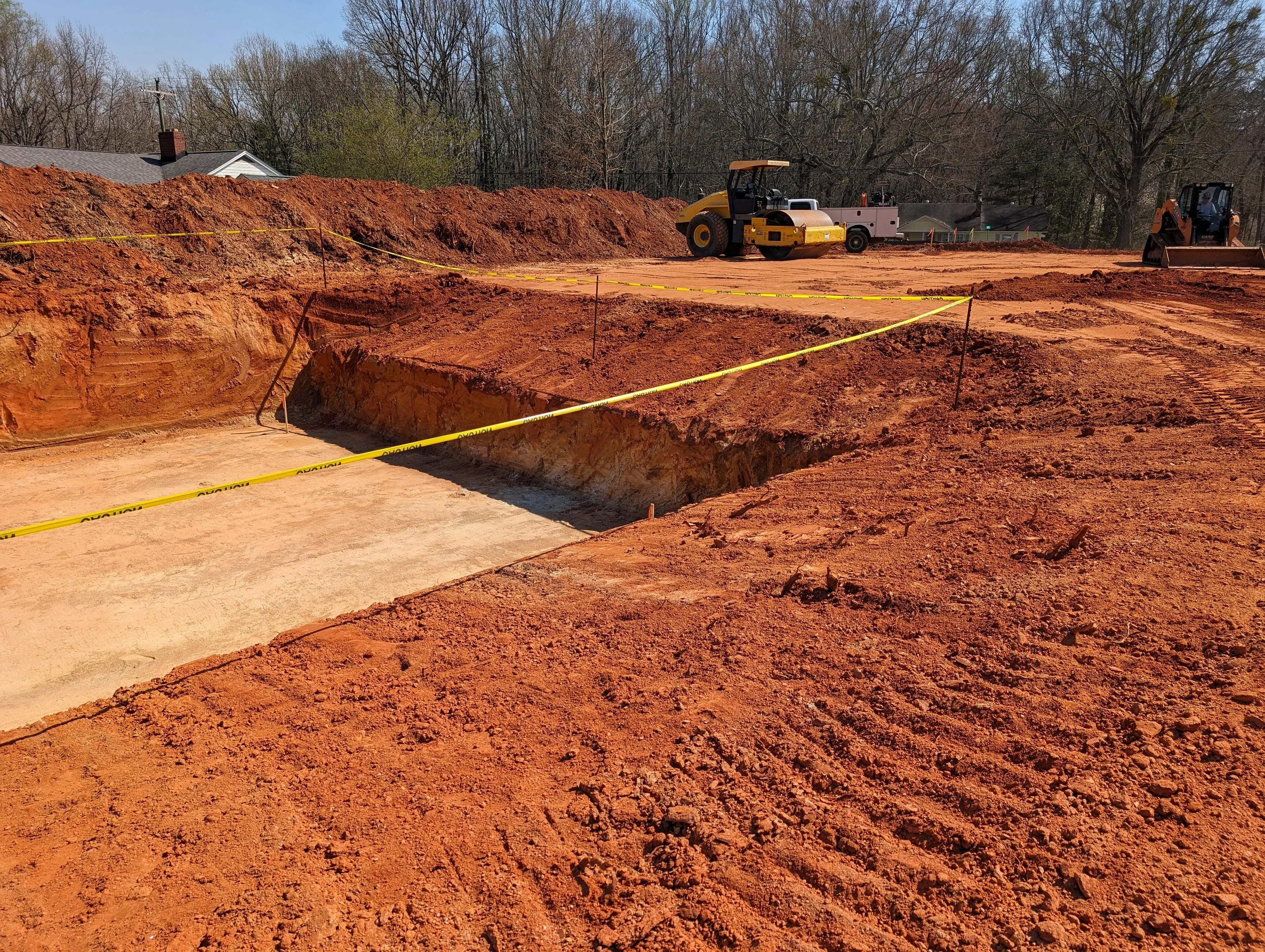 Foundation excavation with multiple depth levels, compacted base, and heavy equipment on-site