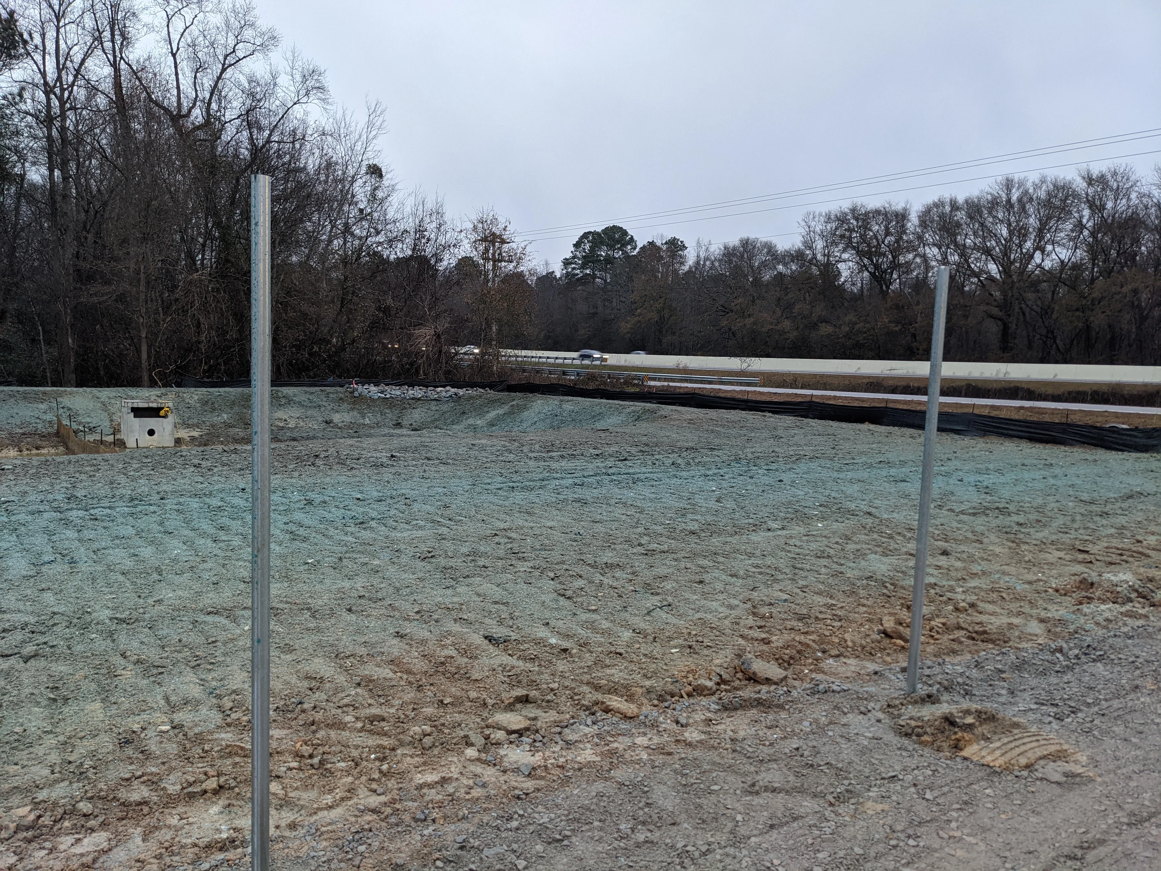 Graded dirt lot with steel posts and compacted earth base