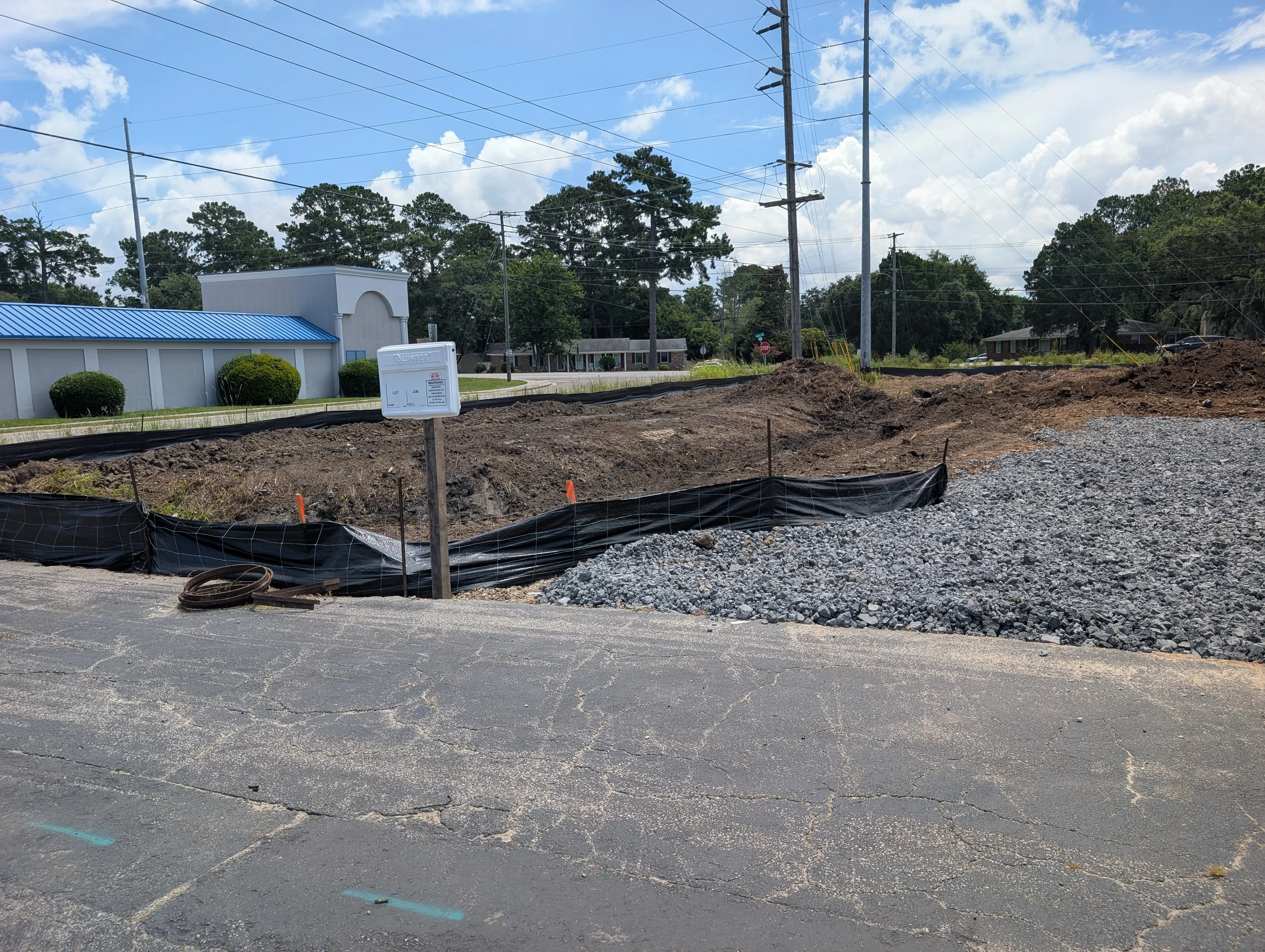 Excavated commercial lot with gravel base, erosion control fabric, and grading work in progress