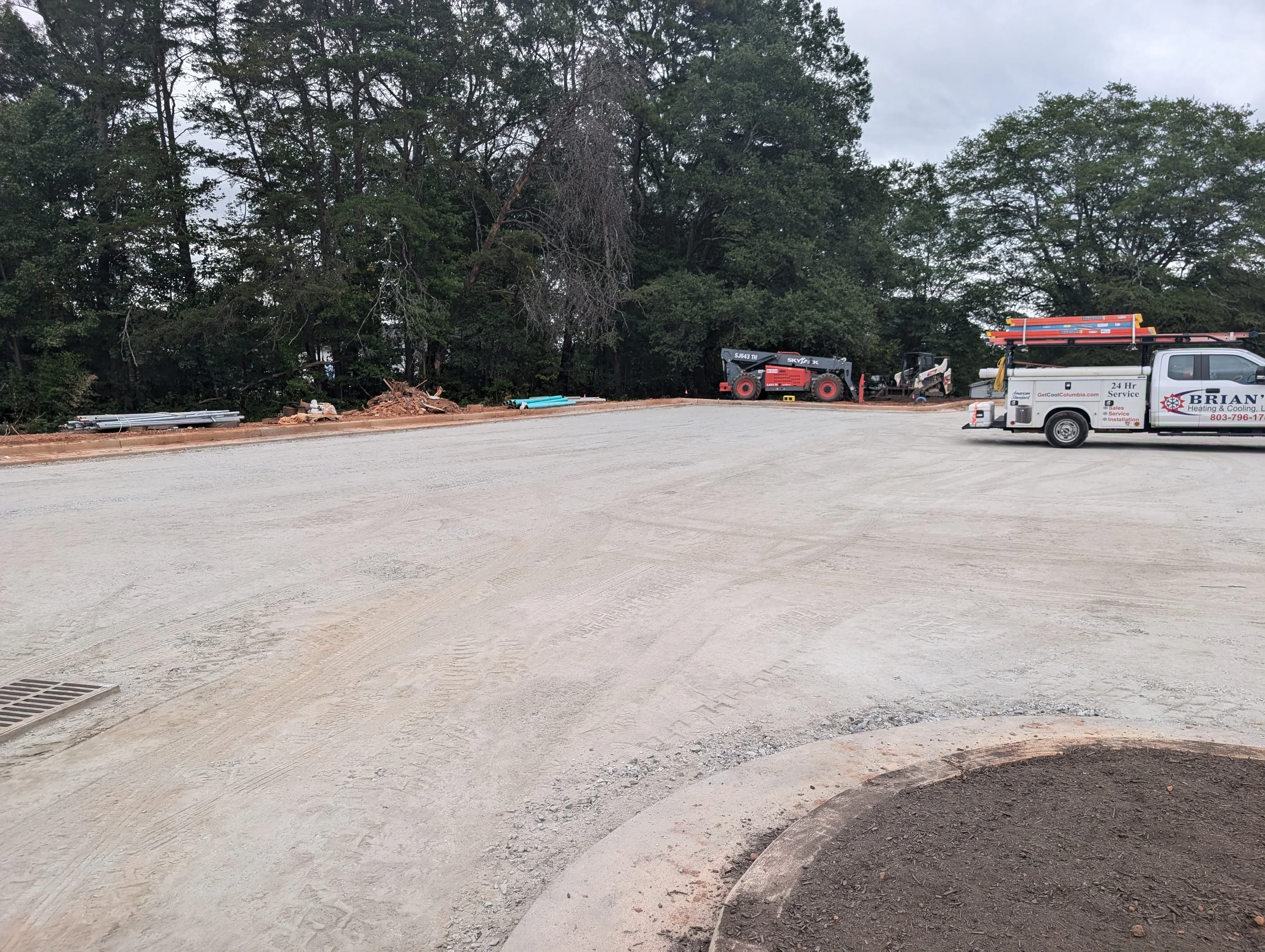 Graded commercial lot with compacted base material, heavy equipment, and cleared staging area