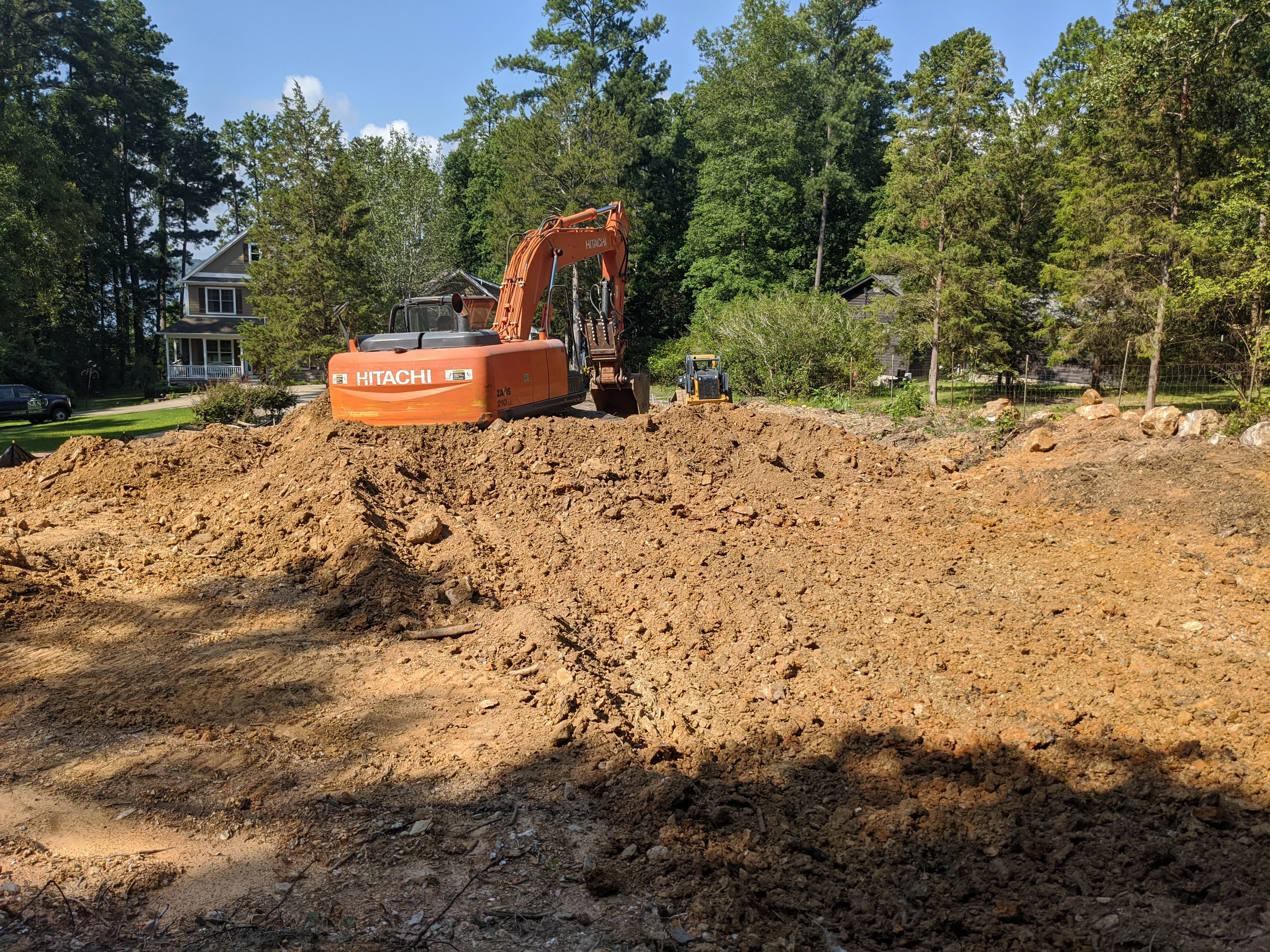 Hitachi excavator moving soil on residential lot during site preparation and grading work